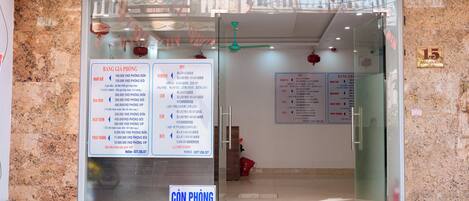 A hotel entrance with a glass door, a signboard with room rates, and a number '15' on the wall.