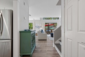 A modern kitchen with a stainless steel refrigerator, a green cabinet, and a white sofa in a bright, open space with a view of the outdoors. - Forest Beach | Walk to Beach, Pool & Tennis, Private Balcony, Sleeps 6 (Hilton Head Island)