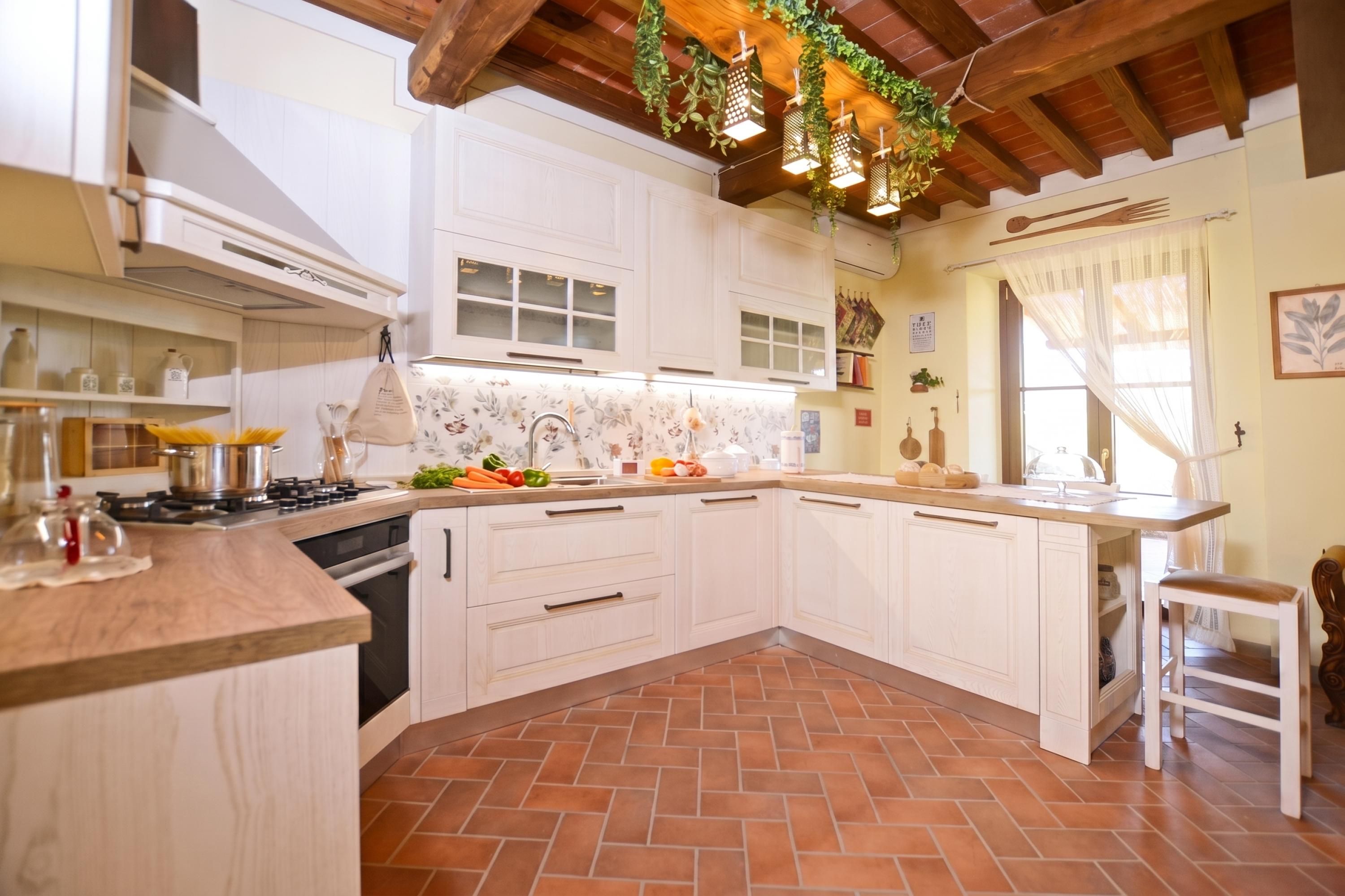 Une cuisine avec des meubles blancs, un sol carrelé et un plafond en bois.