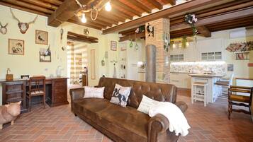 A cozy living room with a brown leather sofa, a wooden desk, and a cat.