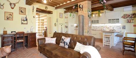Una sala acogedora con un sofá de cuero marrón, un escritorio de madera y un gato.