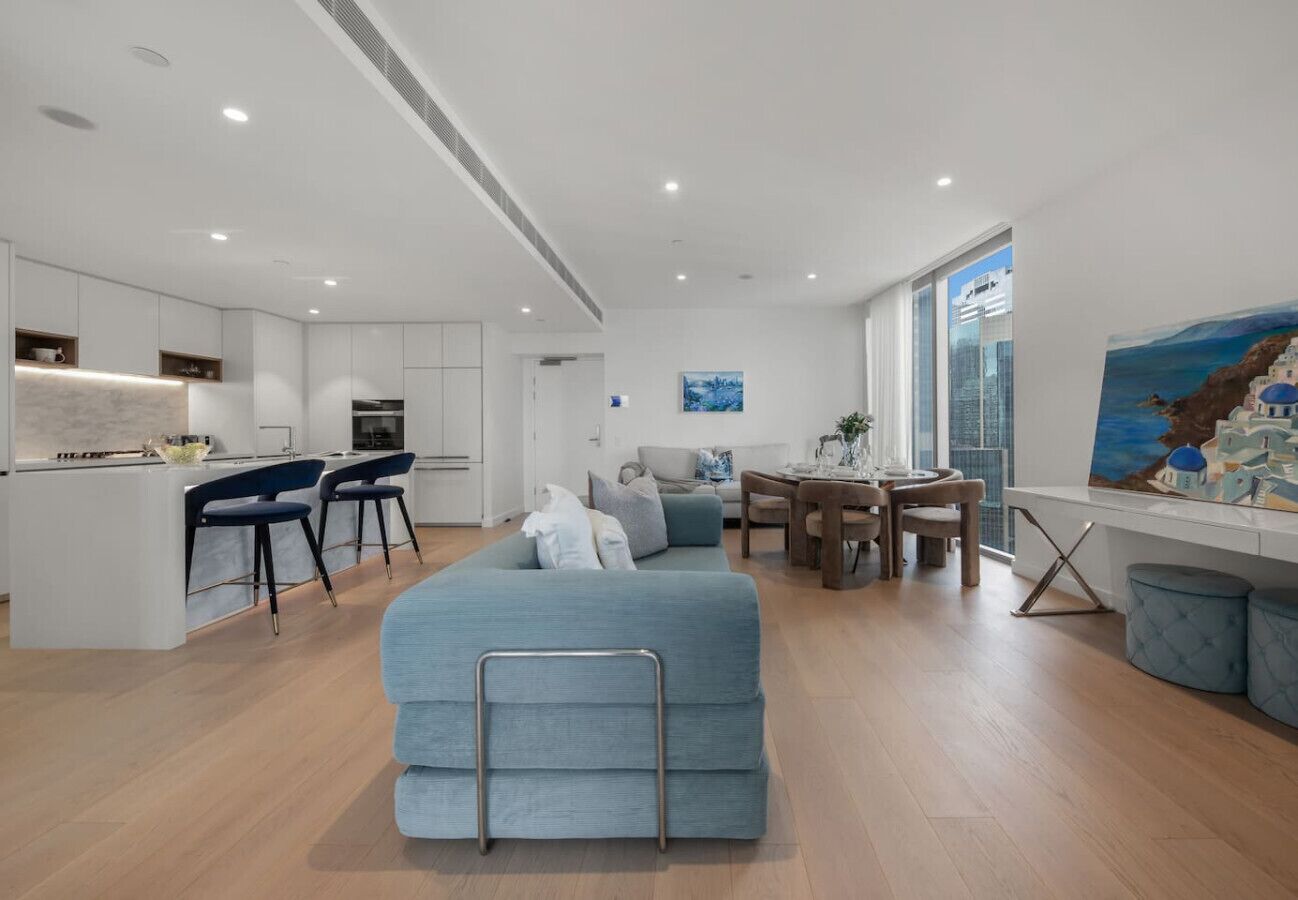 A modern apartment with a kitchenette, a dining area, a sofa, and a painting on the wall.