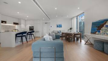 A modern apartment with a kitchenette, a dining area, a sofa, and a painting on the wall.