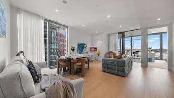 A modern living room with a sofa, a dining table, and a balcony with a view.