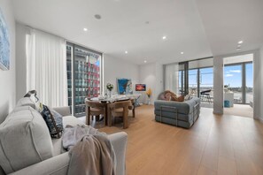A modern living room with a sofa, a dining table, and a balcony with a view. - 海滨CBD/奢华2室/可住6人/海港大桥/悉尼歌剧院 (Barangaroo)