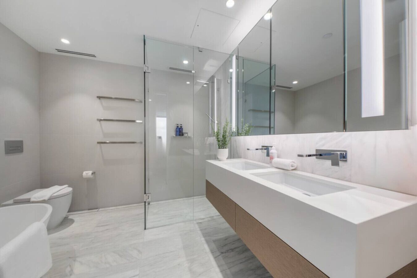 A modern bathroom with a glass shower enclosure, a double sink vanity, and a large mirror.