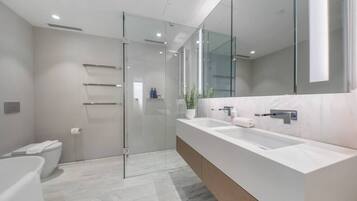 A modern bathroom with a glass shower enclosure, a double sink vanity, and a large mirror.