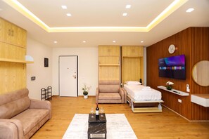 A modern hotel room with a sofa, a bed, a TV, and a wooden wall. - La Dimora Azzurra 103, Vlore, Albania (Vlore)