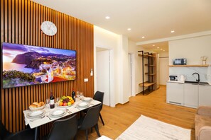 A modern living space with a dining area, kitchen, and a TV displaying a scenic view. - La Dimora Azzurra 102, Vlore, Albania (Vlore)