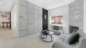 A modern living room with a grey sofa, a round coffee table, and a fireplace. - Spacious 5BR House for 14ppl/Family Gathering/Park (Kingsgrove)