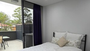 Ein Schlafzimmer mit Bett, einem Sessel, einem kleinen Tisch und Blick nach außen.