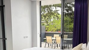 Ein Schlafzimmer mit Bett, Blick ins Freie und einem Essbereich.