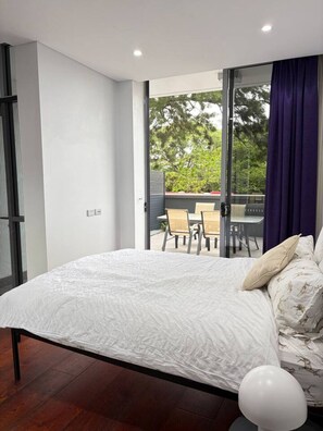 Ein Schlafzimmer mit Bett, Blick ins Freie und einem Essbereich.
