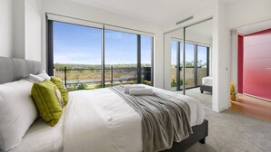 Ein Schlafzimmer mit einem großen Bett, einer Glasschiebetür zu einem Balkon und einer roten Tür.