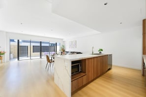 A modern kitchen with a marble countertop, wooden cabinets, and a built-in microwave.