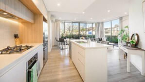 Een moderne keuken met een centraal eiland, een zithoek met een bank en grote ramen met uitzicht.