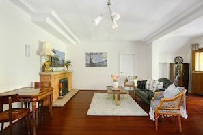 A living room with a fireplace, a dining table, a sofa, and a dartboard.