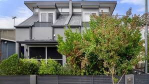 A modern two-story house with a flat roof, a garage, and a well-maintained garden with various shrubs and a tree. - Leichhardt 3-Level Family House | Near CBD (Leichhardt)