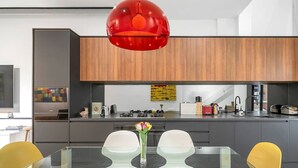 A modern kitchen with a glass dining table, yellow chairs, and a red pendant light. - Leichhardt 3-Level Family House | Near CBD (Leichhardt)