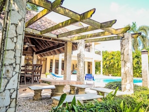 A covered outdoor area with stone pillars, a pool, and a patio with seating.