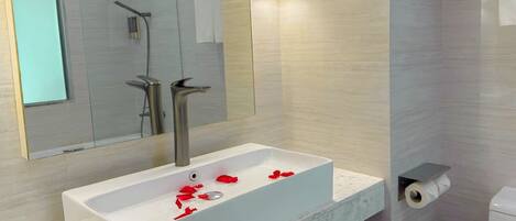 A modern bathroom with a white sink, a mirror, and a toilet.