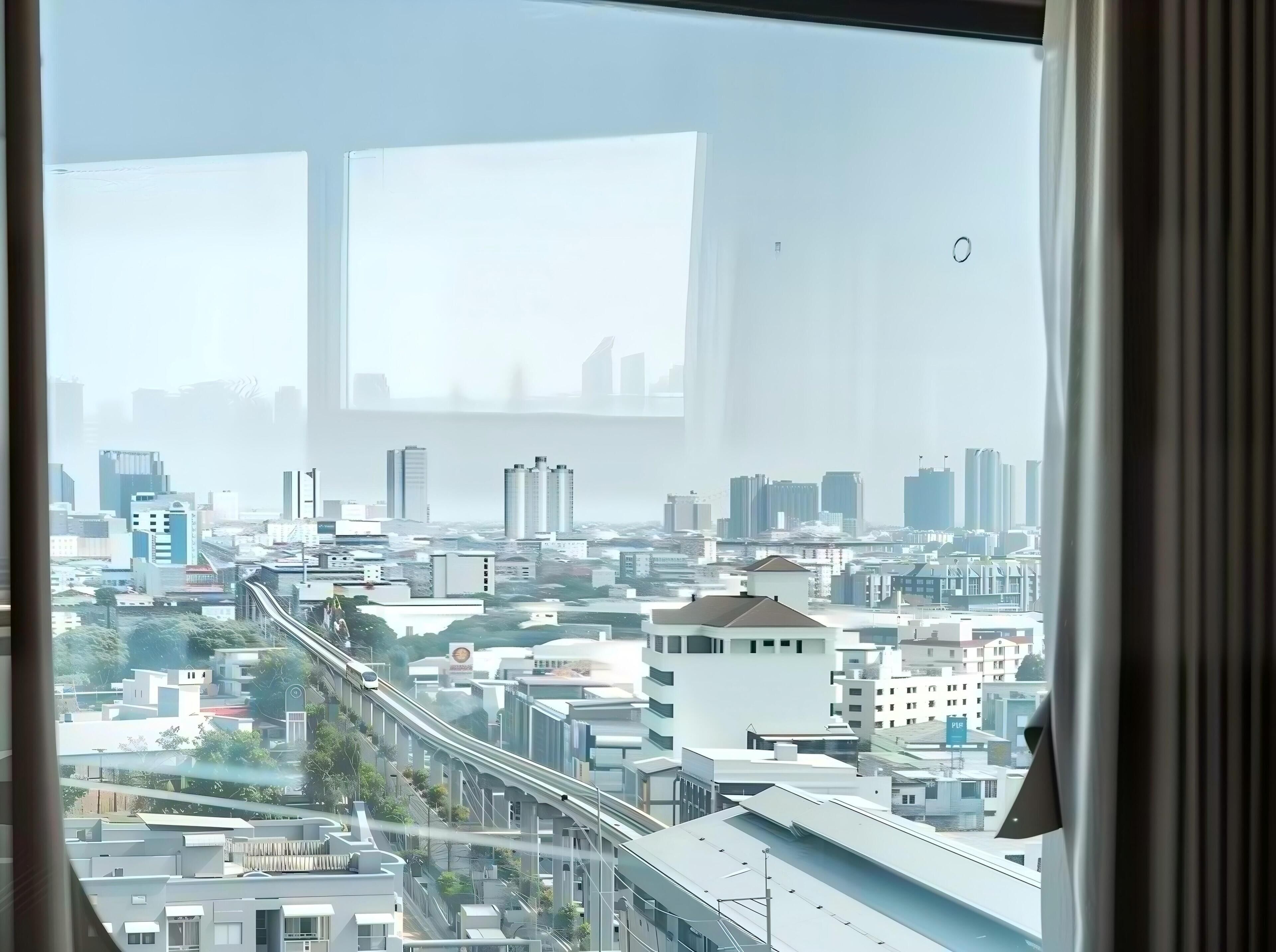 A cityscape view through a window with a clear sky.