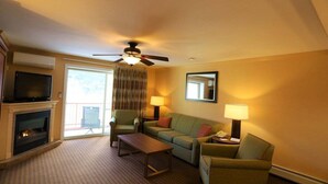 A hotel room with a fireplace, a television, a ceiling fan, a sofa, a coffee table, and two lamps. - PB Sept 18th-20th 1LUM (Lincoln)