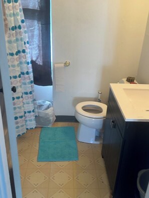 Ein kleines Badezimmer mit Toilette, Waschbecken, Handtuchhalter und Duschvorhang.