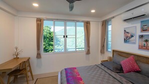 Un dormitorio con cama, escritorio, silla, ventilador de techo y ventana con cortinas.