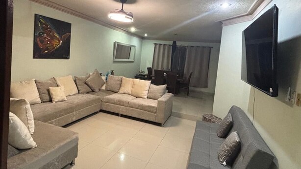 A living room with a sectional sofa, a smaller sofa, a flat-screen TV, a ceiling fan, and a dining area in the background. - World Cup House. 10 Min to Stadium. BBVA & Cerro View (Guadalupe)