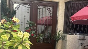 A house with a brown door, a potted plant, a red umbrella, and a tiled patio. - World Cup House. 10 Min to Stadium. BBVA & Cerro View (Guadalupe)