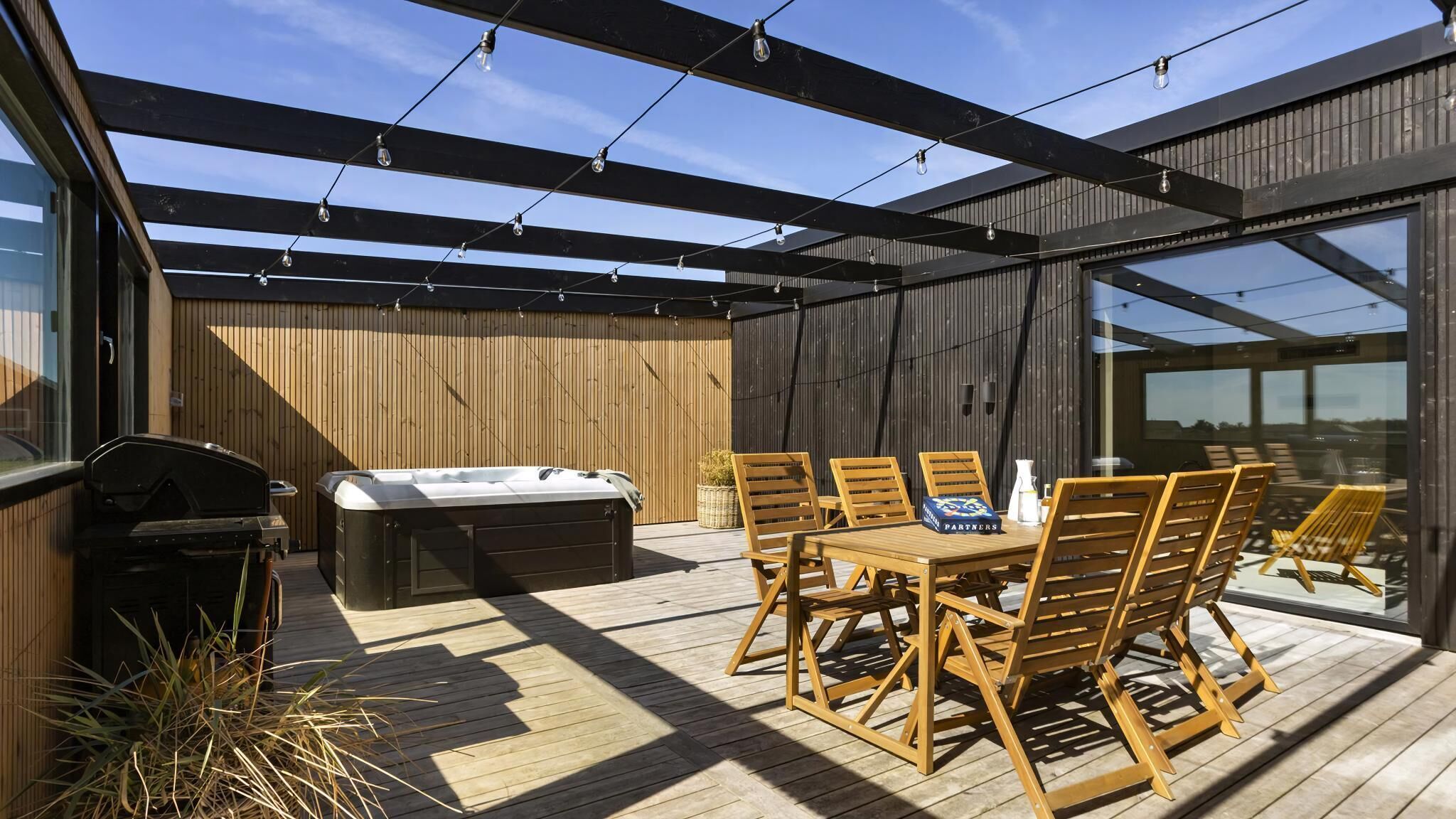 Une terrasse extérieure avec un jacuzzi, une terrasse en bois et une table avec des chaises.