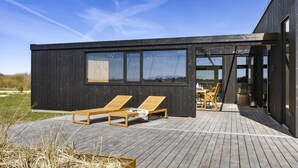A modern building with a deck, two lounge chairs, and a table with chairs. - VillaVilla 965 - Nr. Lyngby ved Løkken, nordjyllan (Løkken)