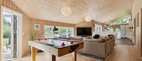 A spacious living area with a foosball table, a large sofa, and a television.