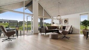 A spacious living area with a large sliding glass door leading to an outdoor patio, a modern sofa set, and a dining table with chairs. - VillaVilla 960 - Østersøbadet, Lolland/Falster/Møn (Rødby)