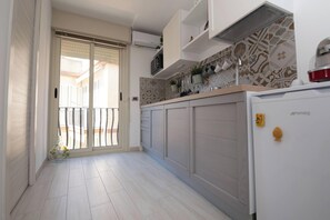 Una cucina moderna con una porta scorrevole che dà su un balcone, un forno a microonde integrato e un frigorifero.