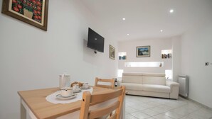 Uma sala de jantar com uma mesa, cadeiras e uma televisão fixada na parede.