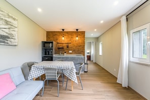 Un espace de vie compact comprenant un coin cuisine, un coin repas avec une table à carreaux et un canapé.