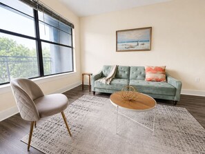 Un salon avec un canapé, un fauteuil, une table basse et un tableau accroché au mur.