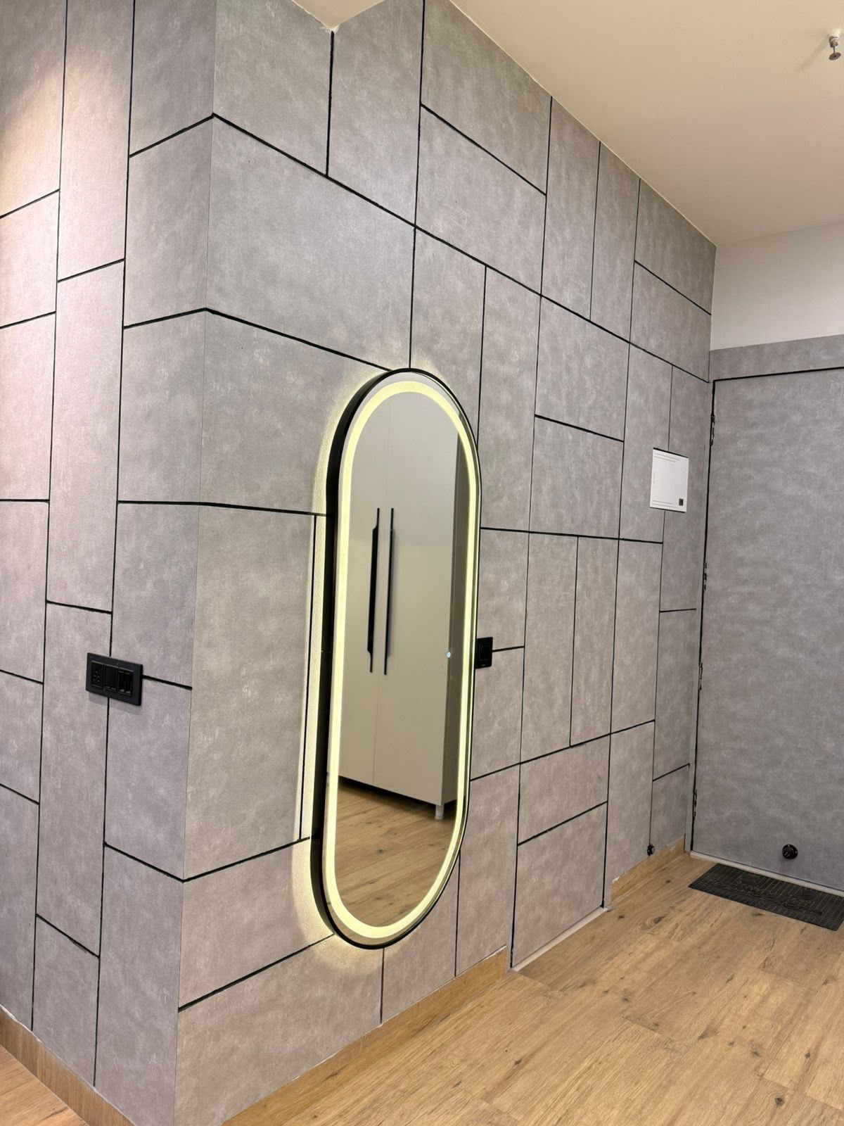Una habitación con pared de azulejos, un espejo y suelo de madera.