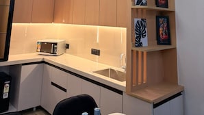 Una cucina moderna con forno a microonde integrato, un lavello e una mensola in legno con opere d'arte.