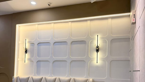 Una camera da letto moderna con un letto, comodini e una testiera con illuminazione integrata.