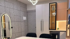 Zona pranzo moderna con tavolo bianco, sedie nere e un lampadario originale.