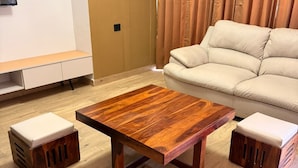 Un soggiorno con un tavolino in legno, due pogiadari, una divano e una televisione a parete.