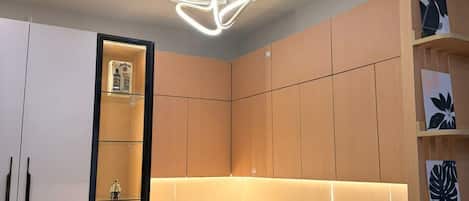 A modern kitchen with a built-in microwave, a refrigerator, and a unique geometric pendant light.