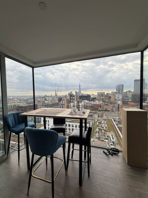 Ein Hotelzimmer in einem Hochhaus mit Blick auf die Stadt, einem Tisch und zwei Stühlen.
