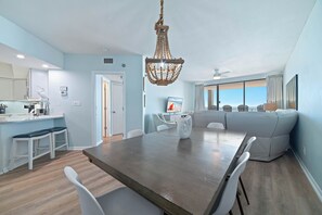 A modern kitchen with a dining area, a chandelier, and a large window. - Beachfront Condo w/ Huge Balcony, Sleeps 11, Pools & Gulf Views | BEACHBALL PROPERTIES (Orange Beach)