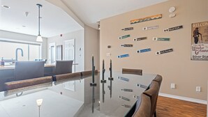 A modern dining area with a glass table, leather chairs, and a wall decorated with directional signs. - Ultimate Slopeside Retreat – Sleeps 24 Across Two Spacious Townhomes (Silver Star Mountain)
