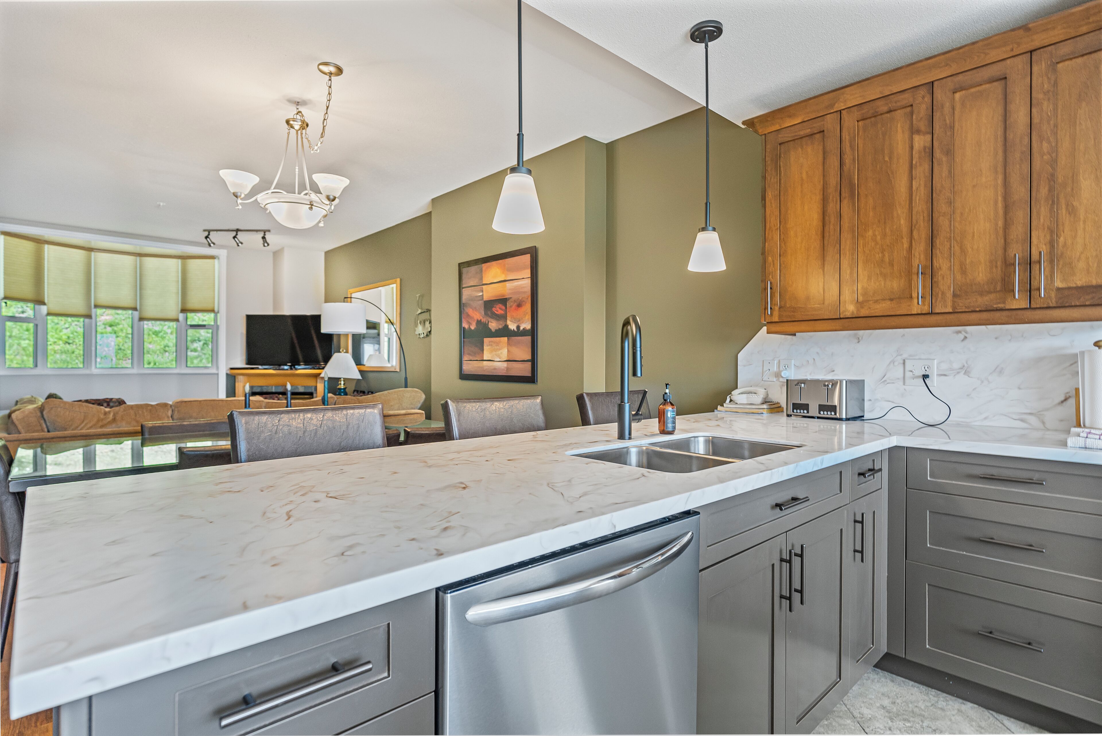 A modern kitchen with a marble countertop, stainless steel appliances, and wooden cabinets.