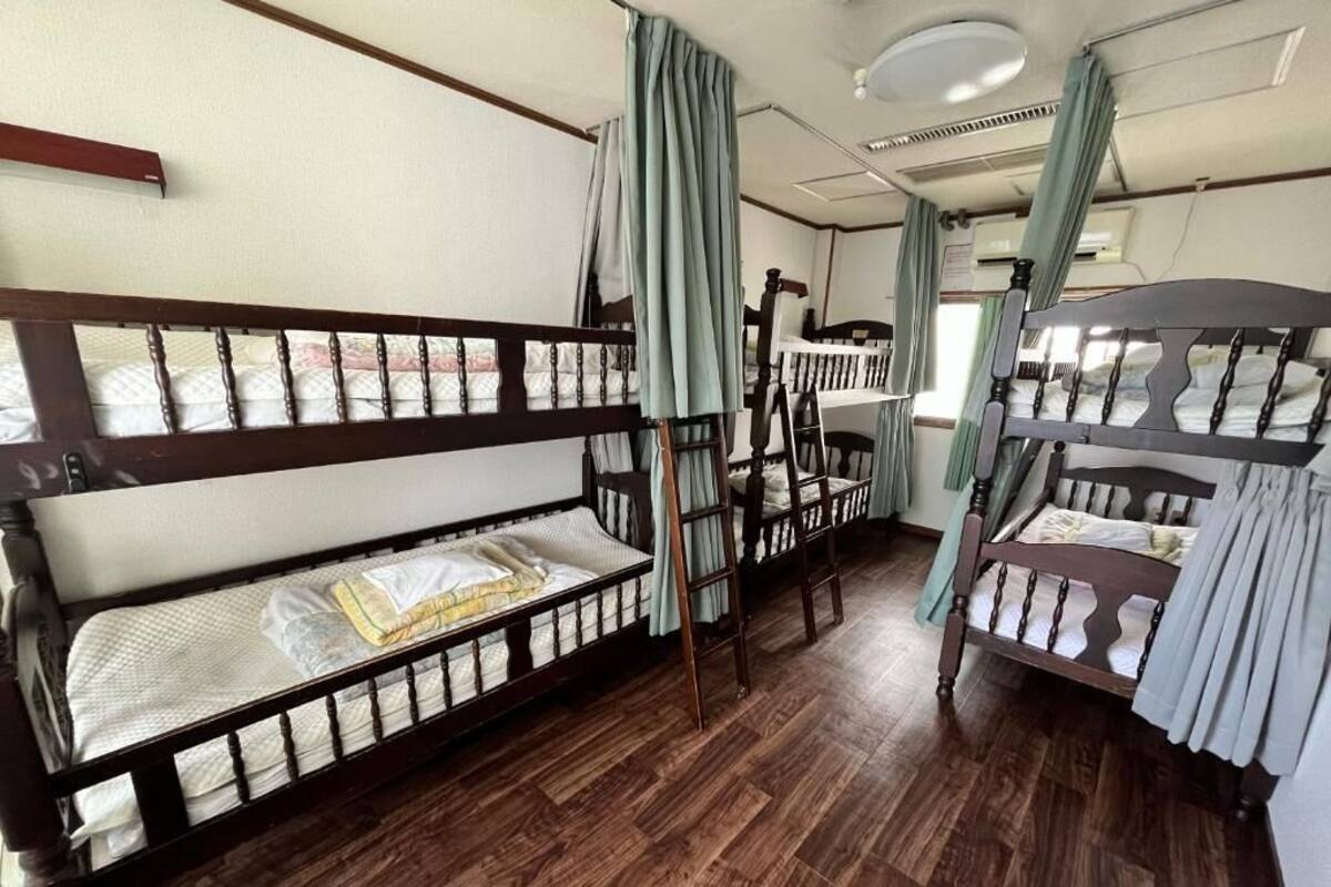 A room with bunk beds, wooden flooring, and curtains.